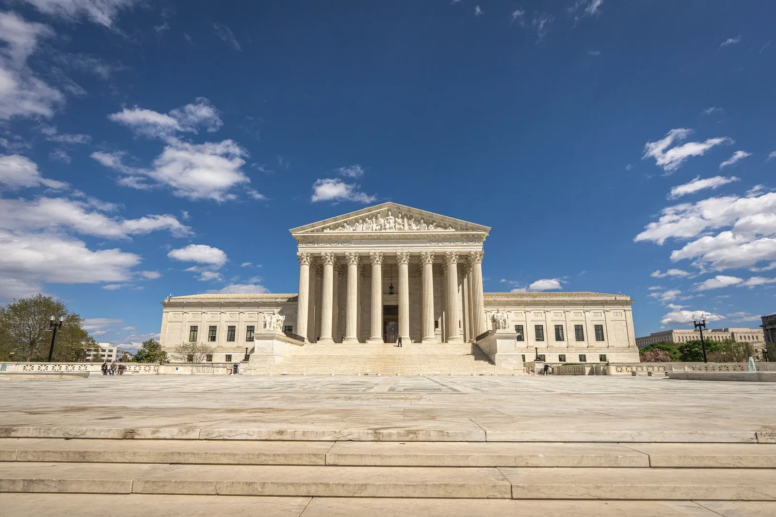 Front view of the U.S. Supreme Court building in Washington, D.C., under a blue sky with scattered clouds
