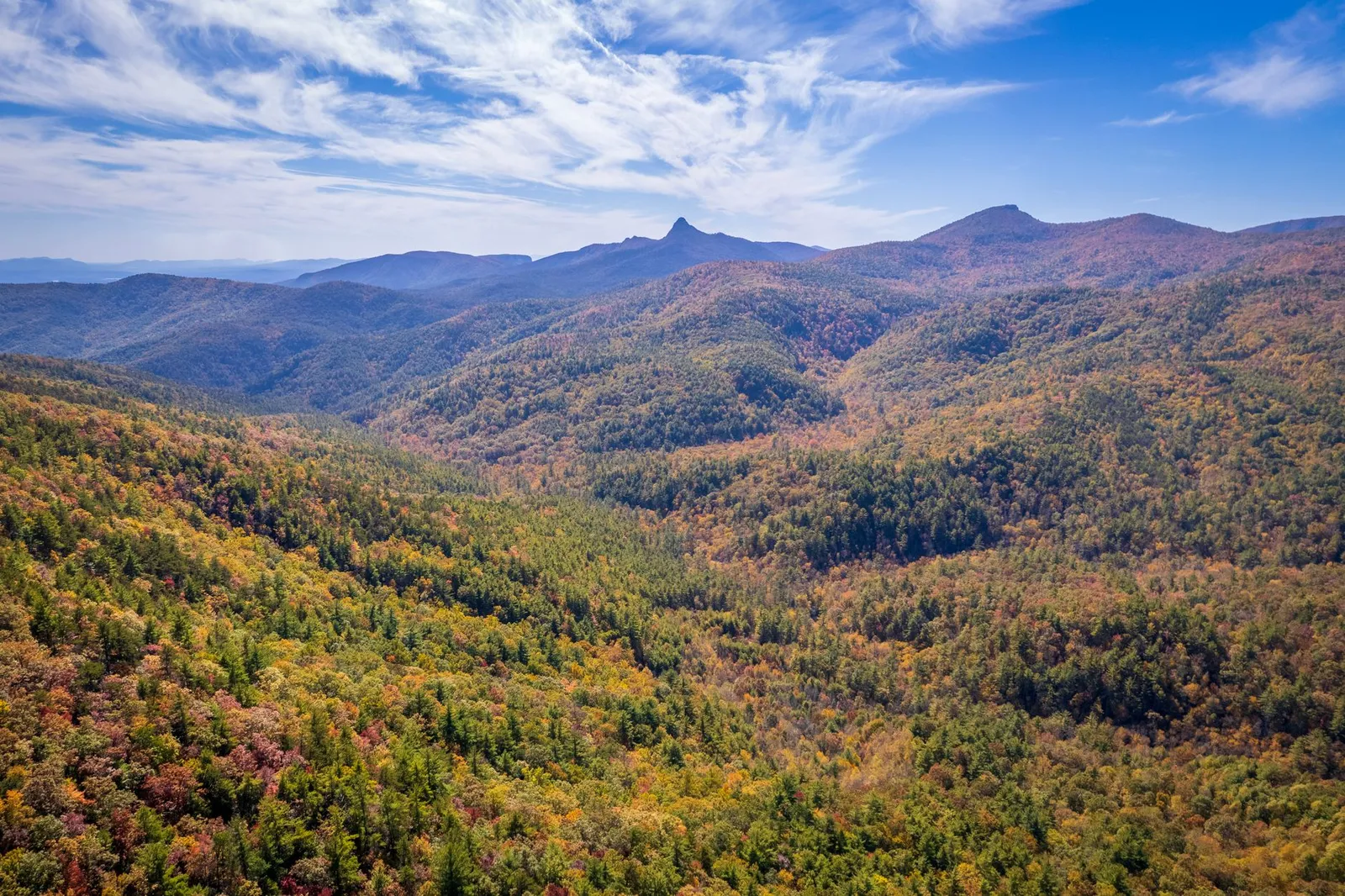 Aerial view of autumn forested Appalachian mountains and ridgelines under a blue sky in North Carolina