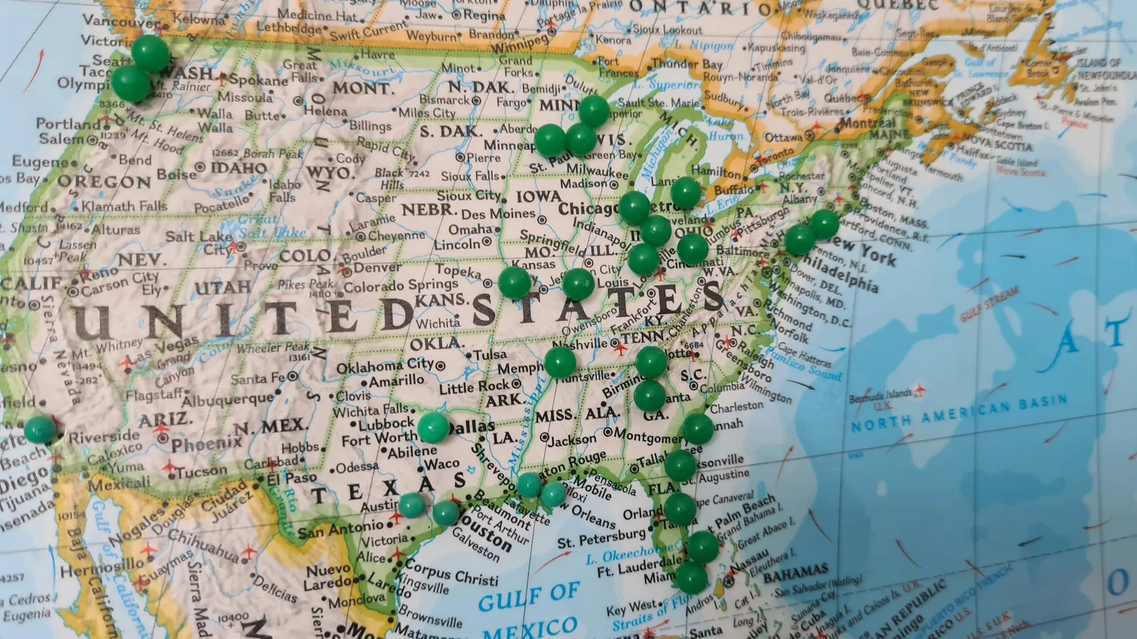 A close view of a U.S. map with green pushpins marking locations across states and counties