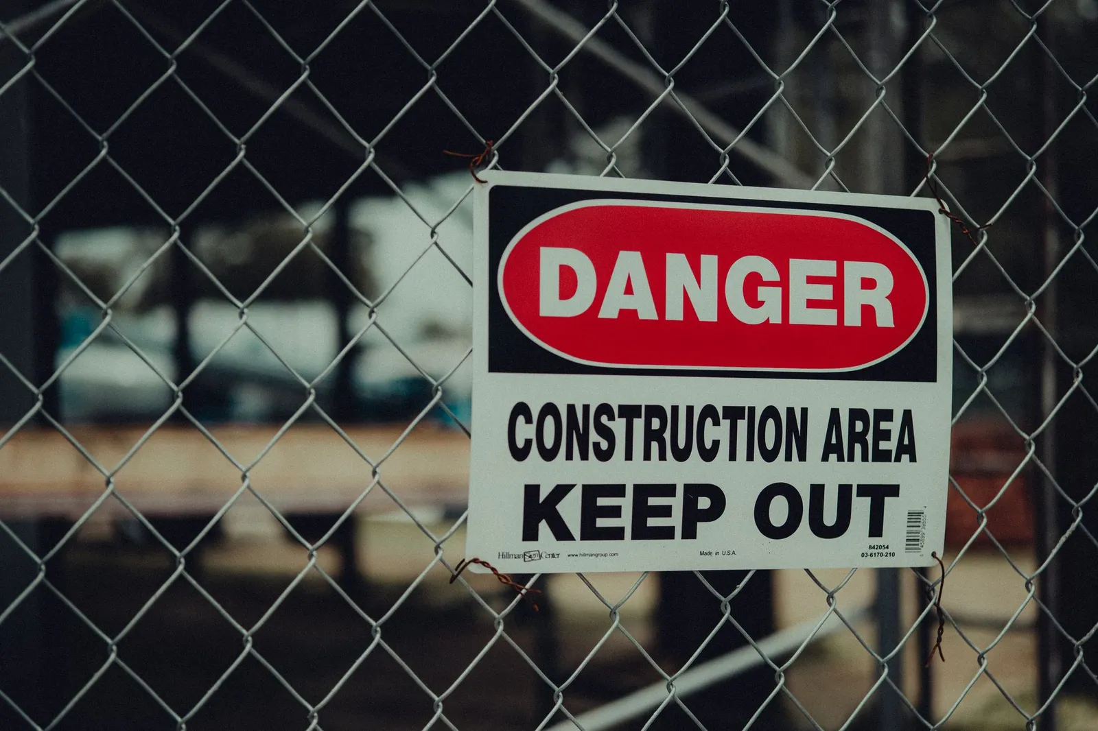 Close-up of a danger sign on chain-link fencing marking a construction area with keep-out warnings